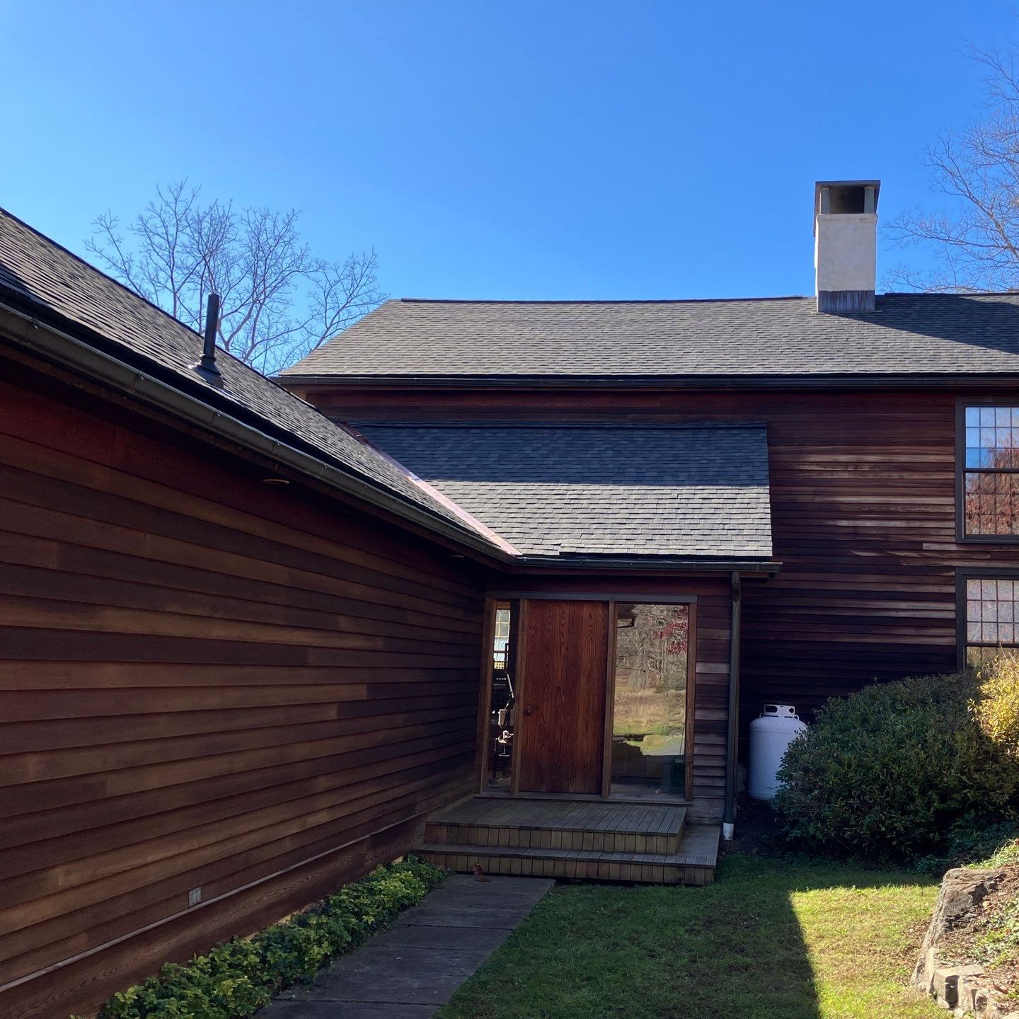 A person is holding a hammer in front of a roof A person is holding a hammer in front of a roof
