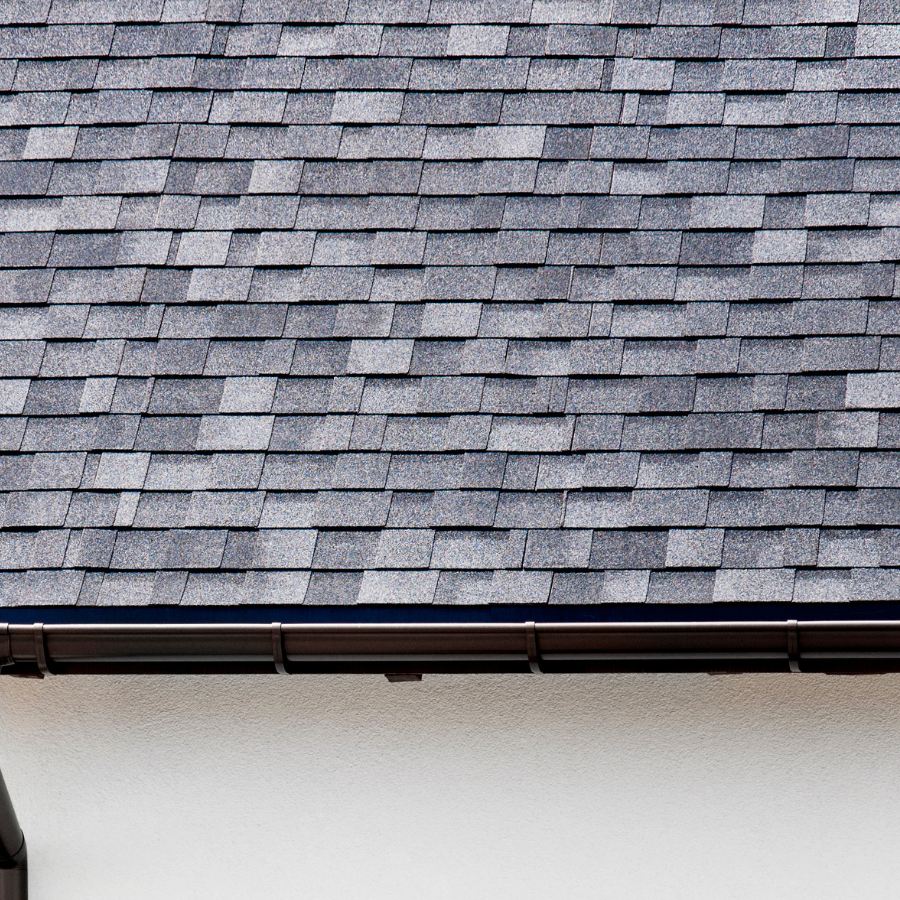 A close up of a roof with shingles and a gutter. A close up of a roof with shingles and a gutter.