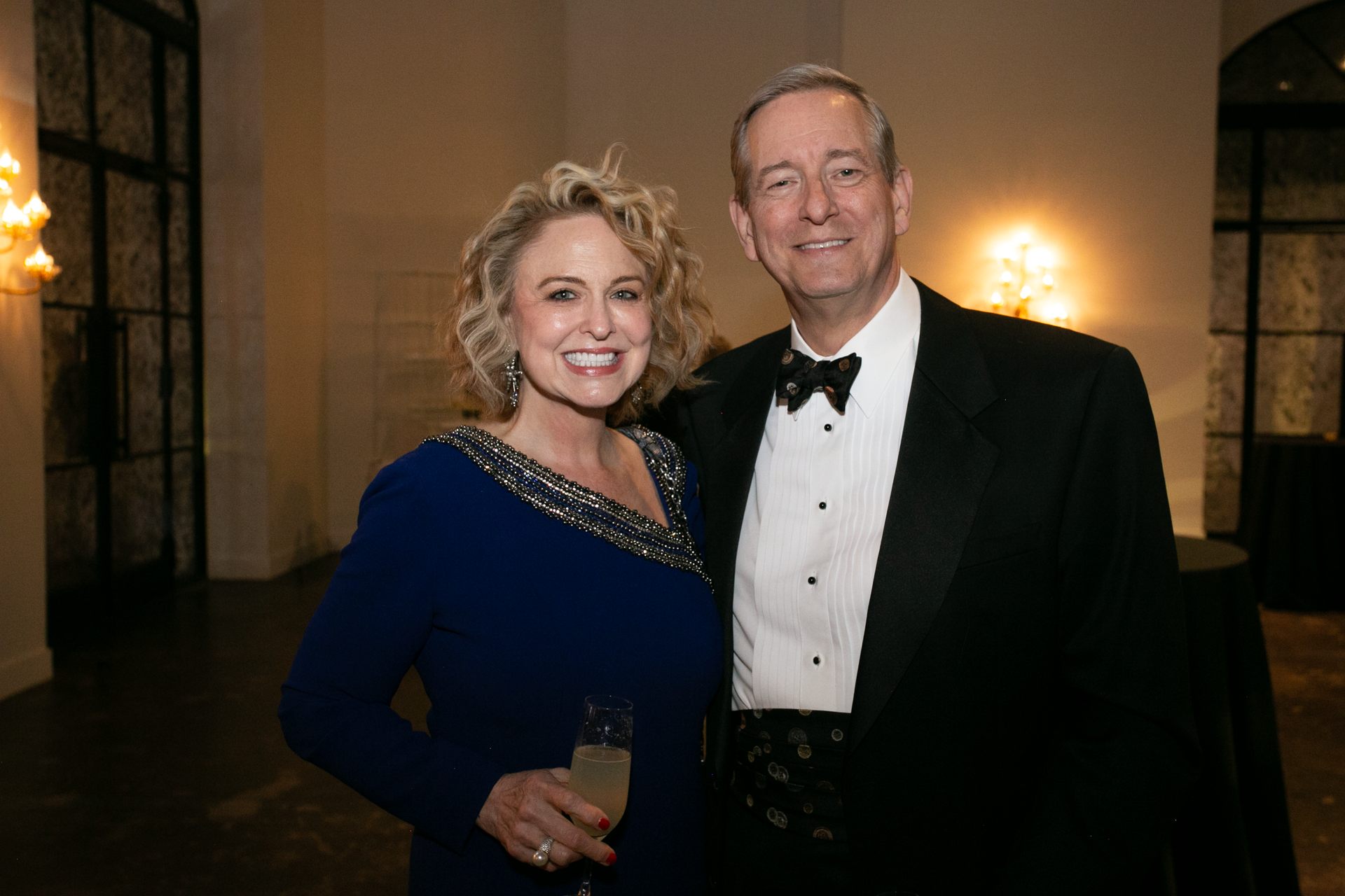 A man in a tuxedo and a woman in a blue dress are posing for a picture.