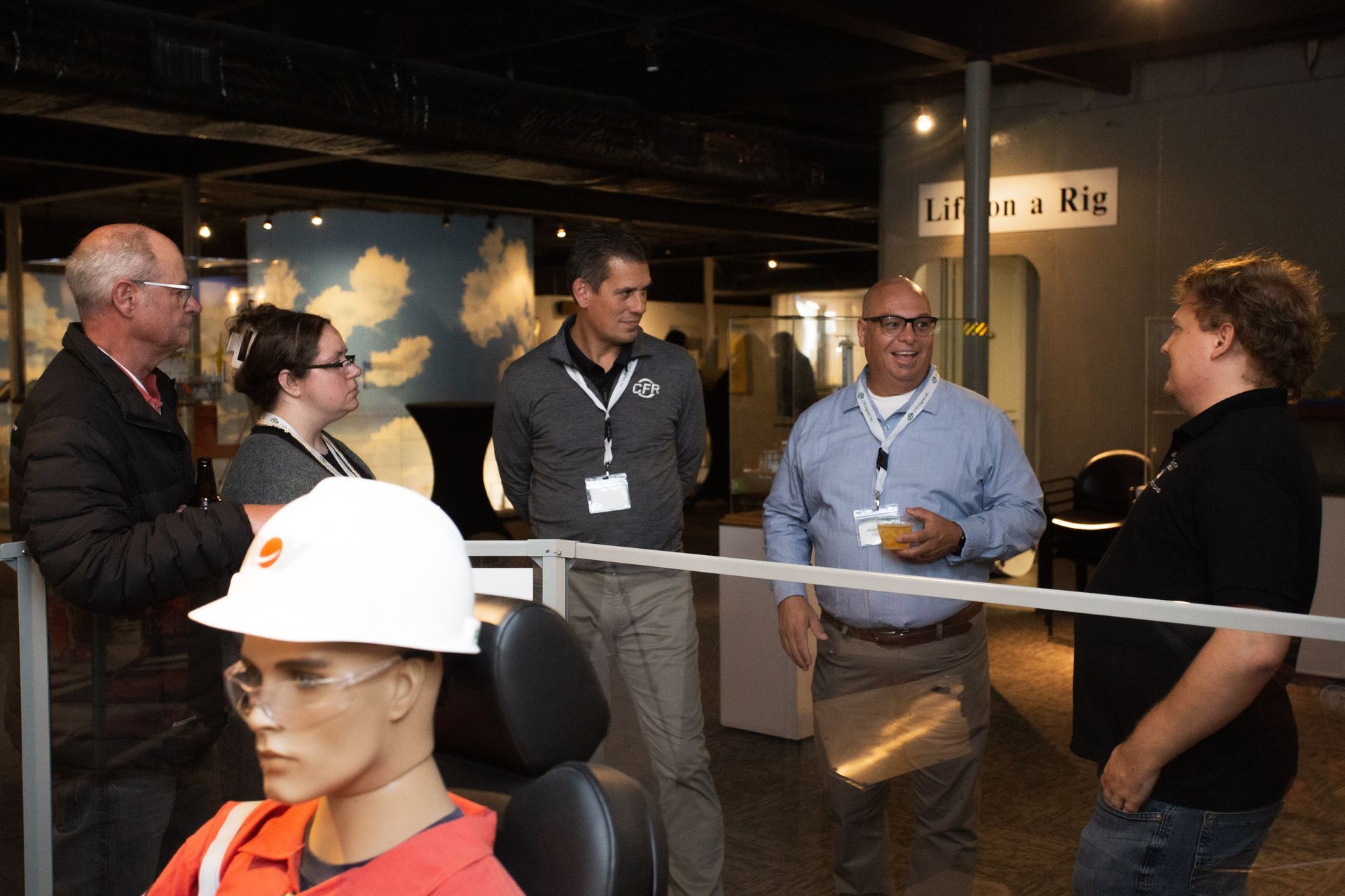 A group of people converse in a museum exhibit labeled 