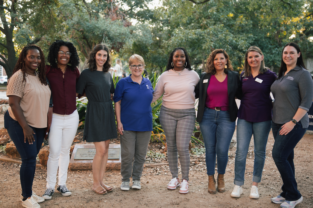 A group of women are standing next to each other in a park.