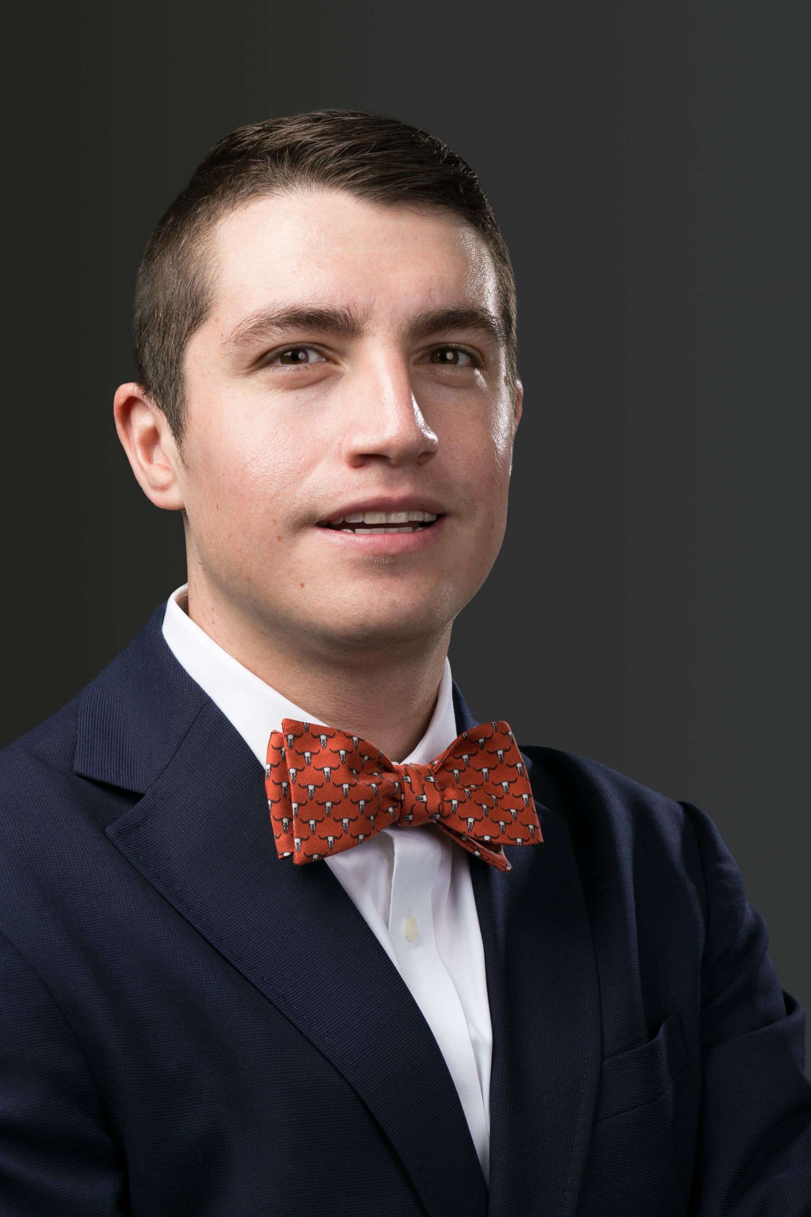 A man in a blue suit and white shirt is standing in a dark room.