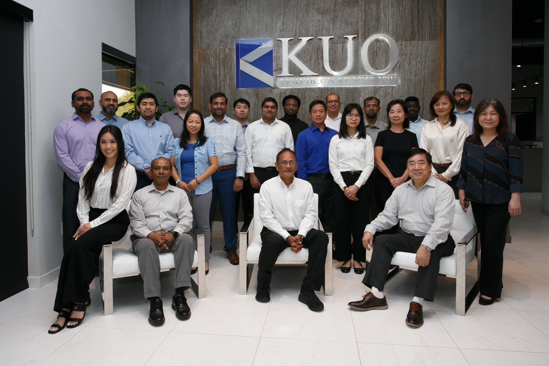 A group of people are posing for a picture in front of a kuo sign.