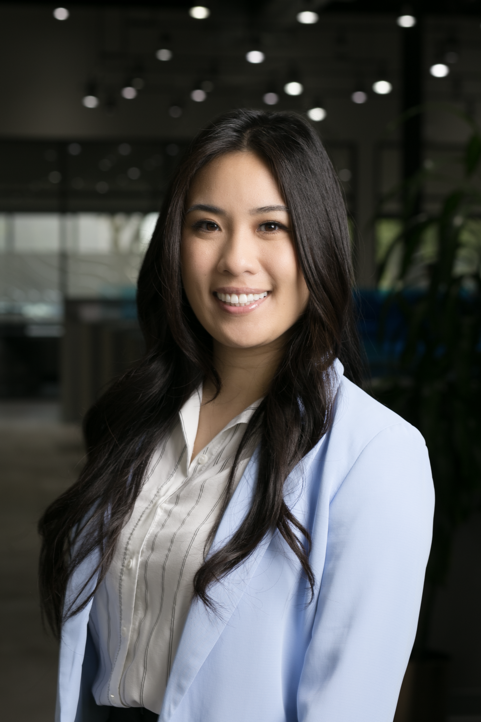 A woman in a blue jacket and white shirt is smiling for the camera.
