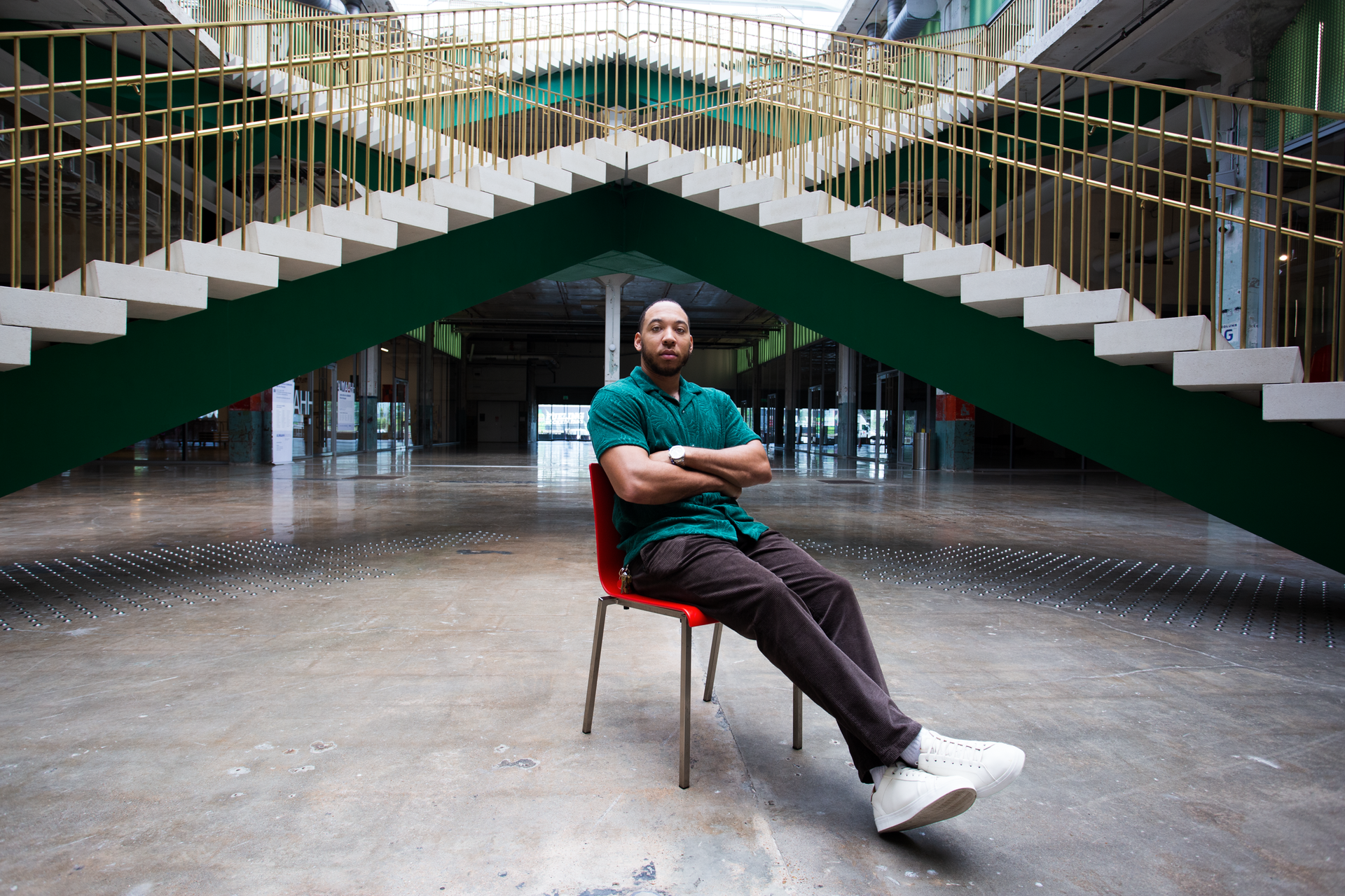 A man is sitting in a chair in front of stairs.