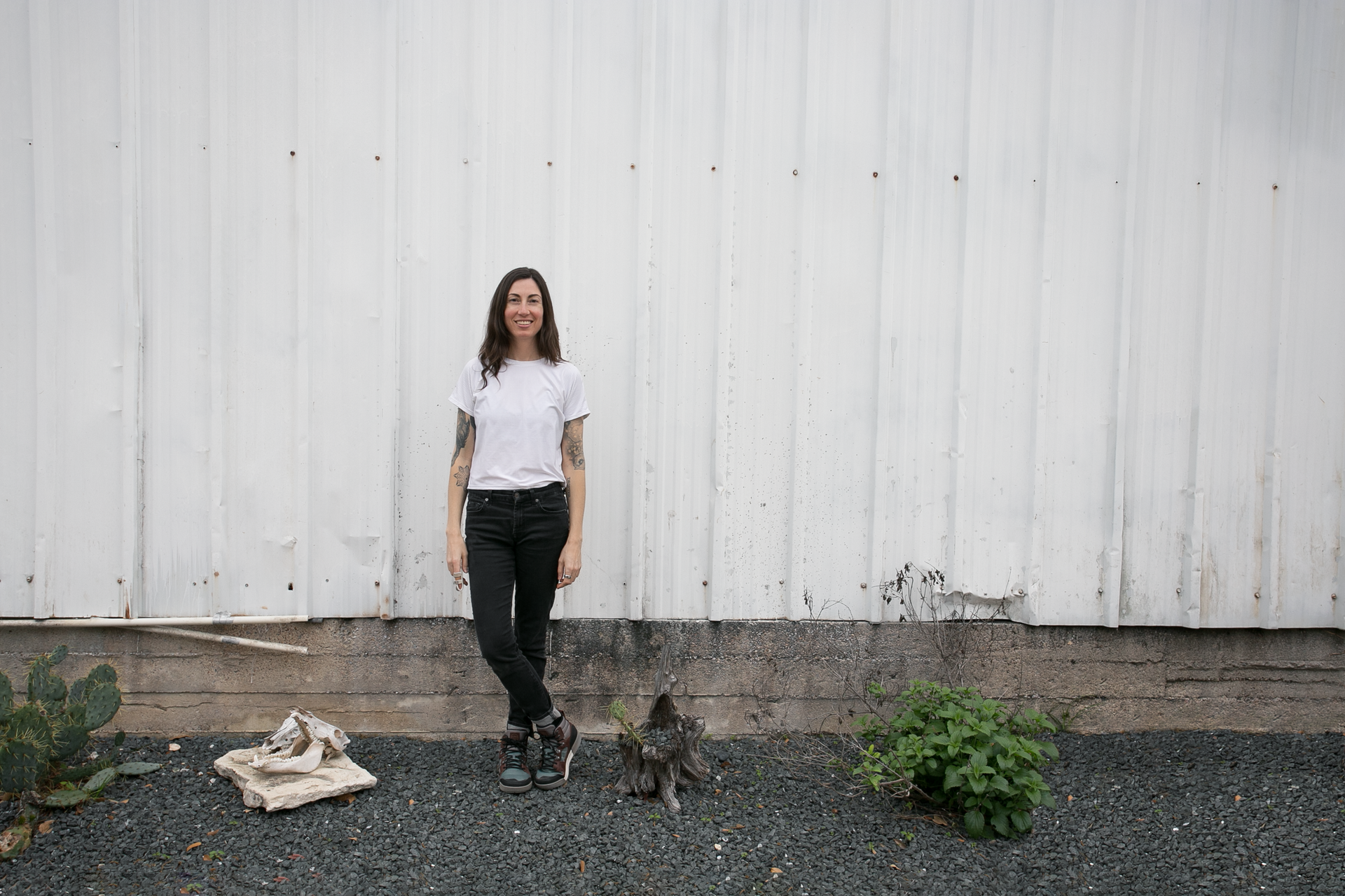 A woman is standing in front of a white wall next to a dog.