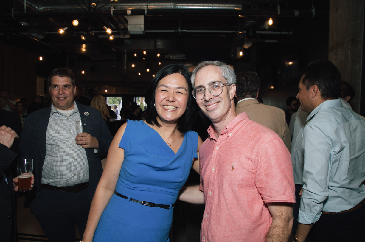 A woman in a blue dress is posing for a picture with a man in a pink shirt.