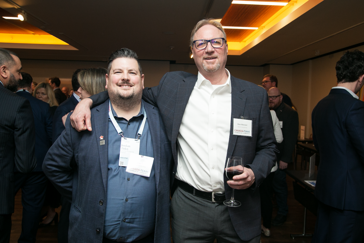 Two men are posing for a picture in a crowded room.