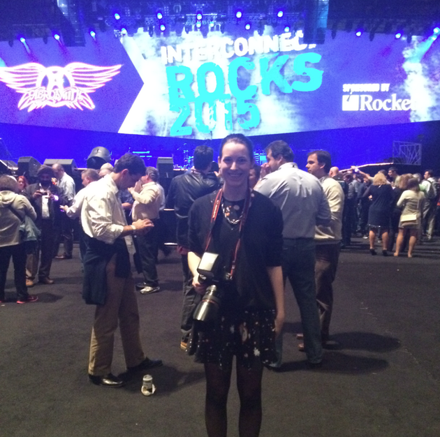 A woman stands in front of a large screen that says rocks 2013