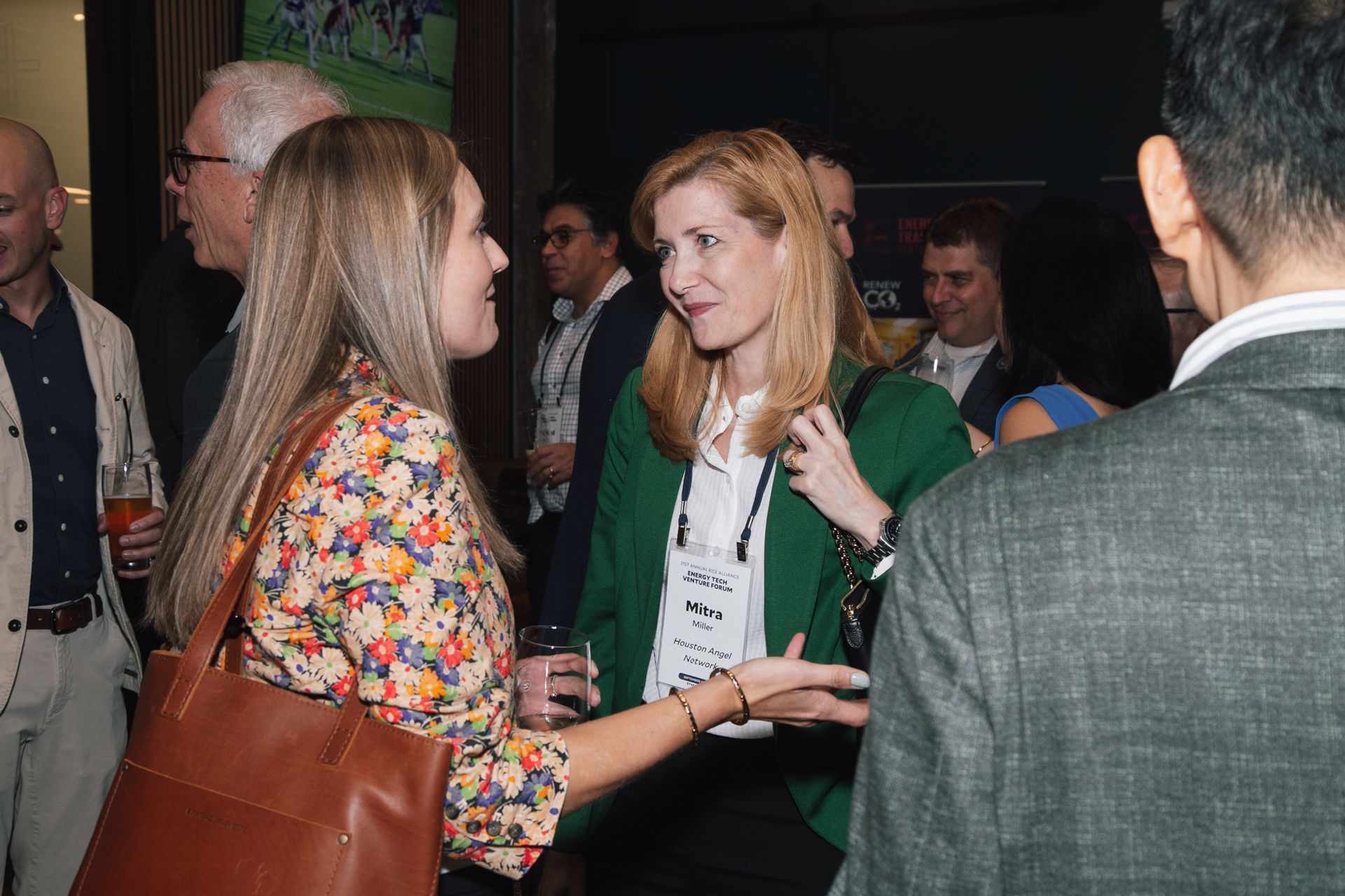 People conversing at a professional networking event in a dimly lit, indoor venue.