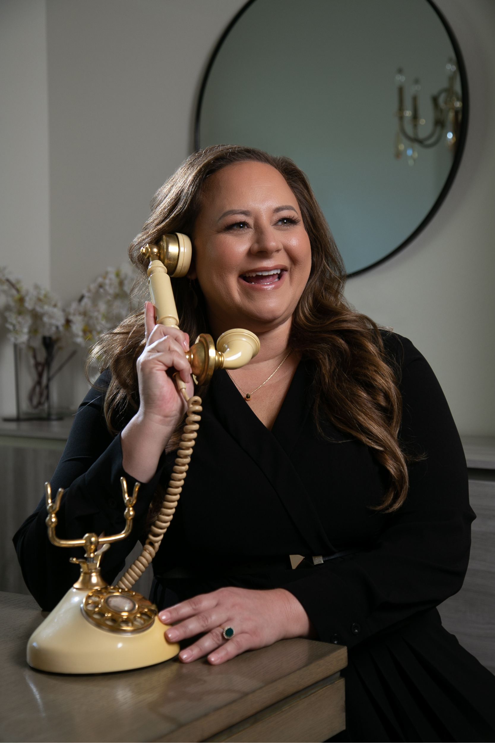 A woman is sitting at a table talking on a yellow telephone.