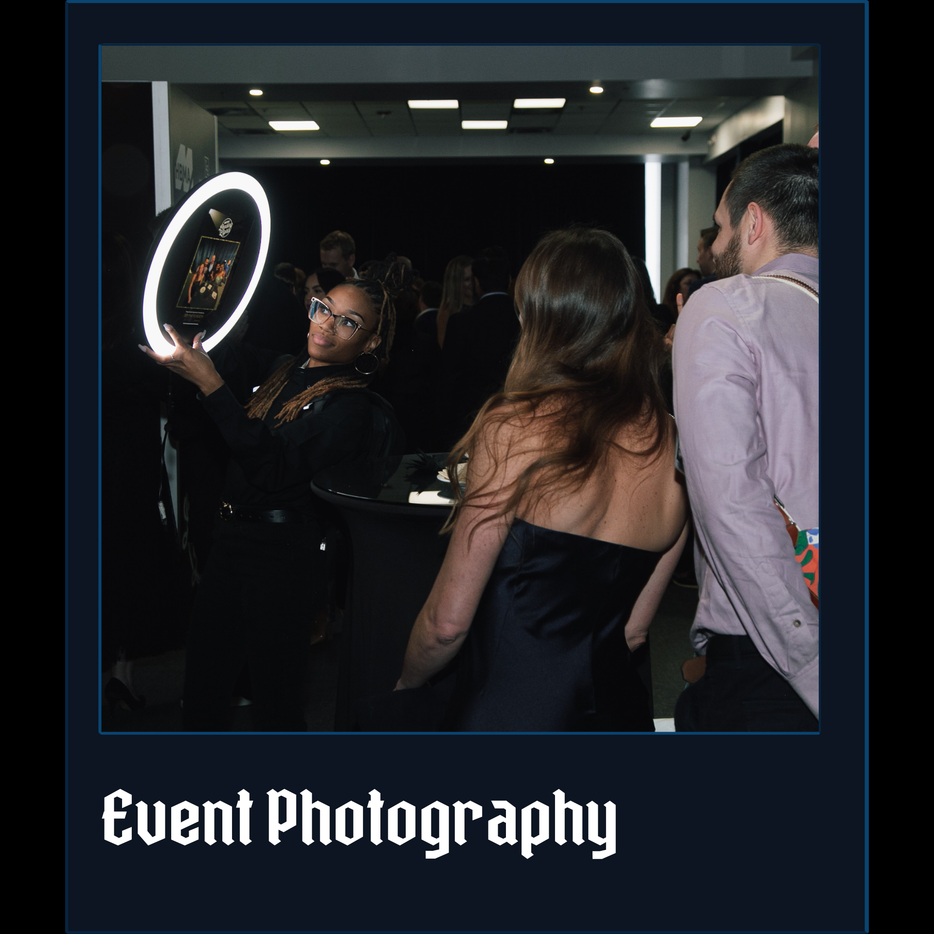 A woman in a black dress is taking a picture of herself in a photo booth.