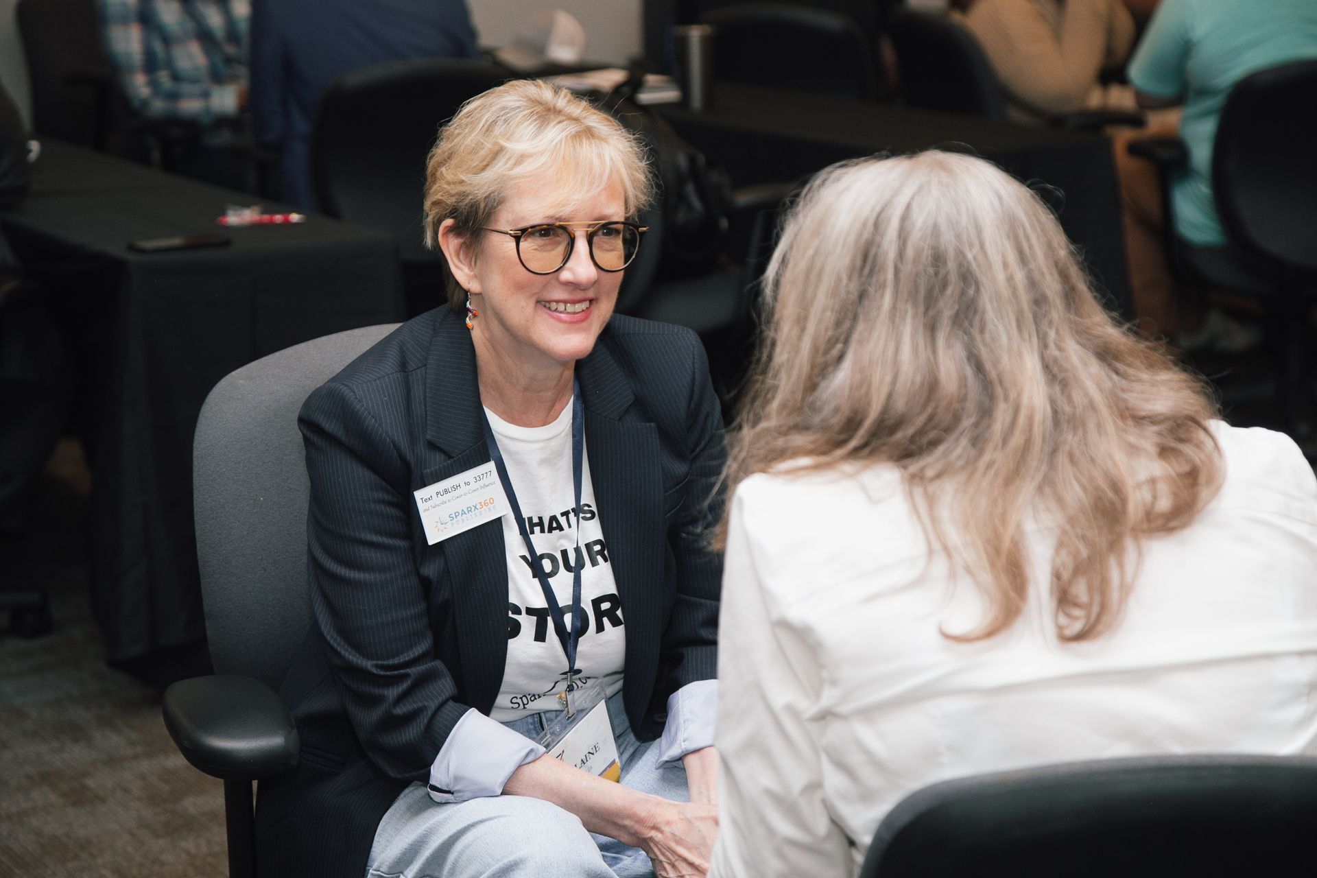 Two people sit facing each other in a conference room, engaged in conversation.
