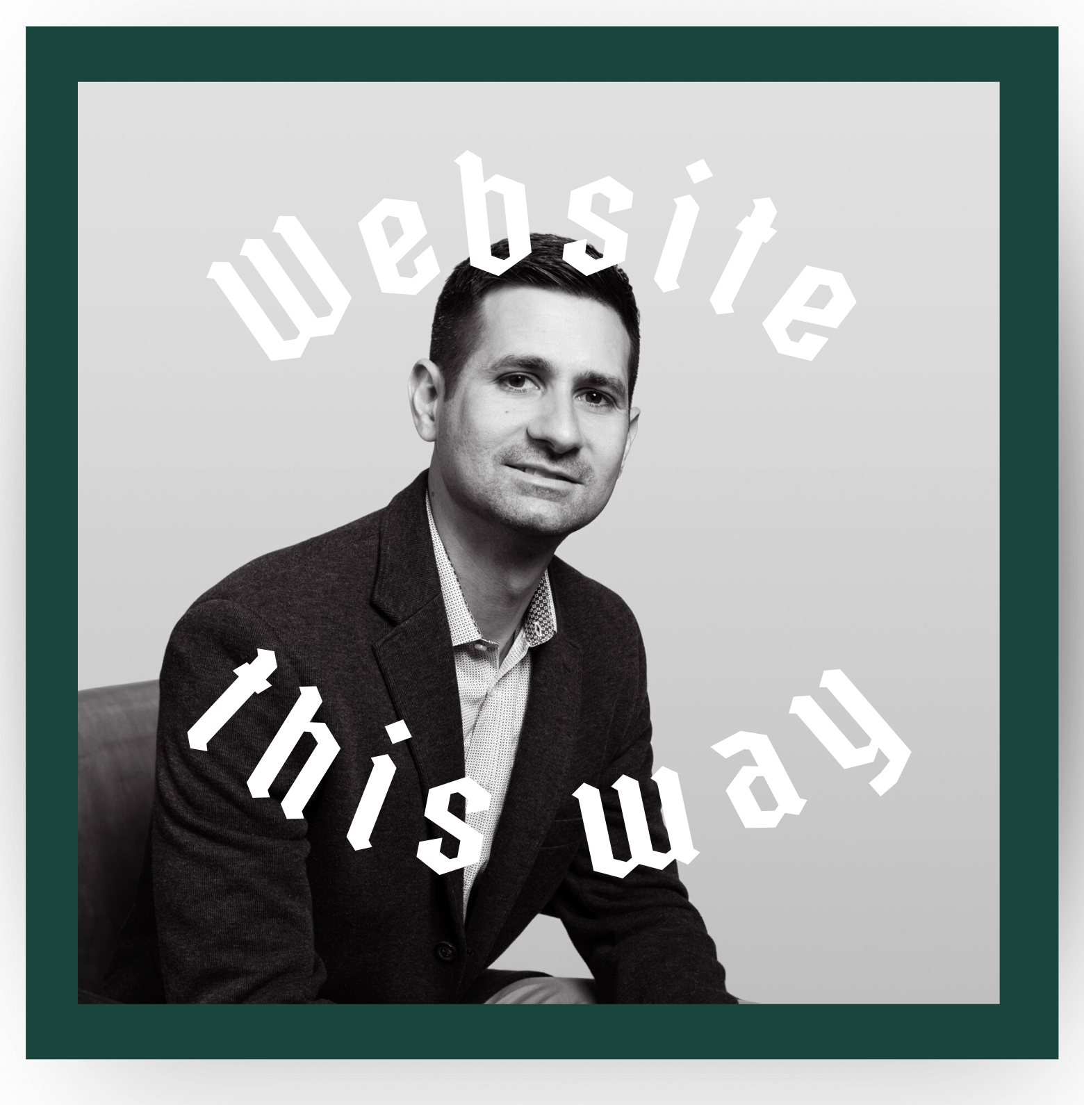 A man in a suit is sitting in front of a sign that says website this way