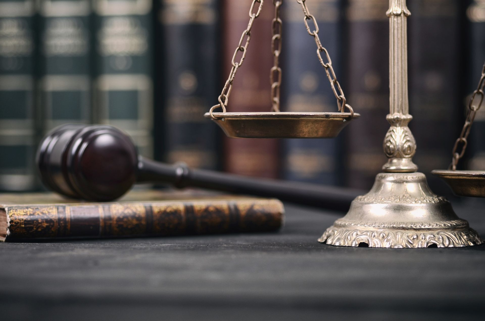 Scales of justice, gavel, and books on a dark surface, symbolizing law and order.