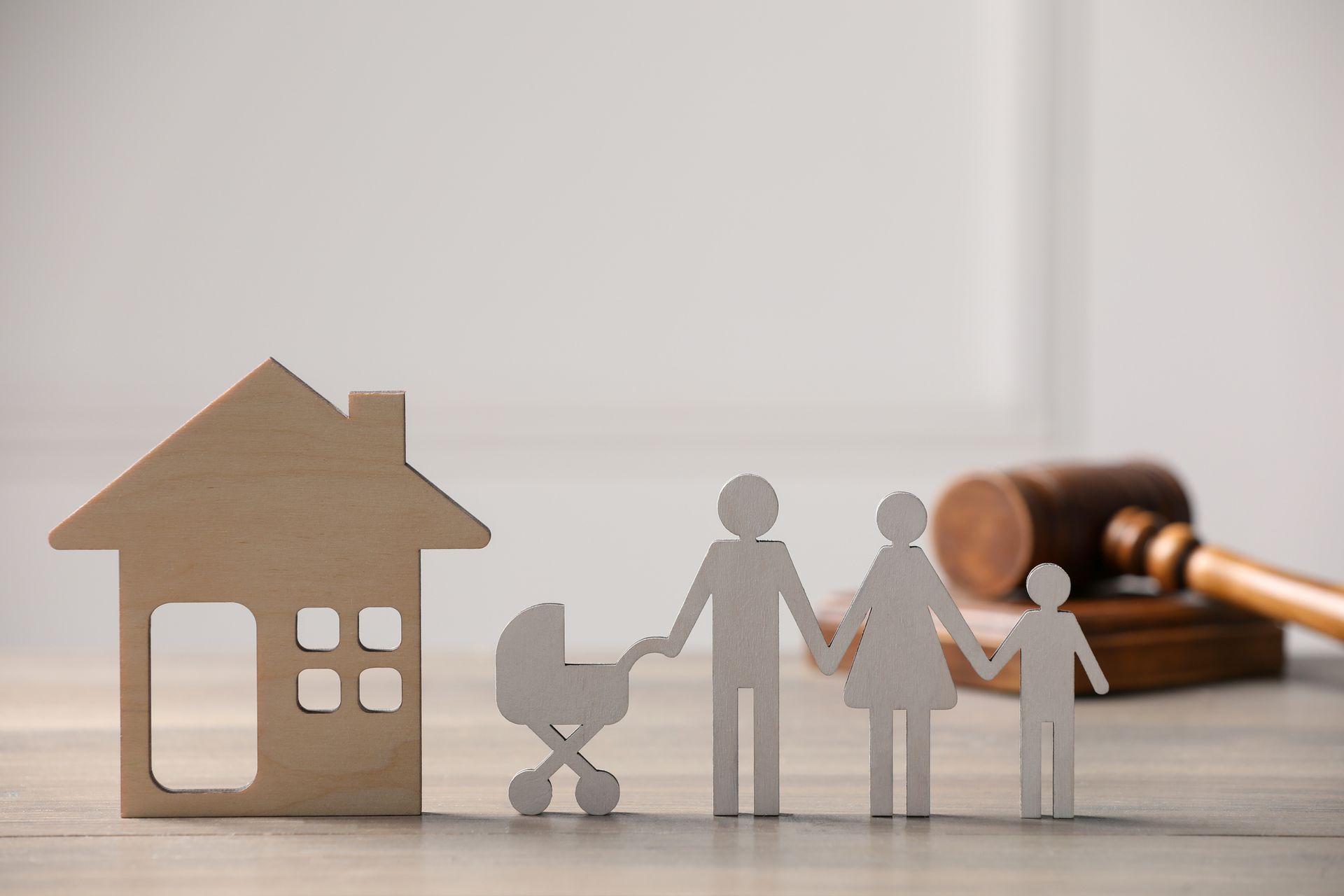 Wooden house, family cutout, and gavel on a table, symbolizing family law or real estate.