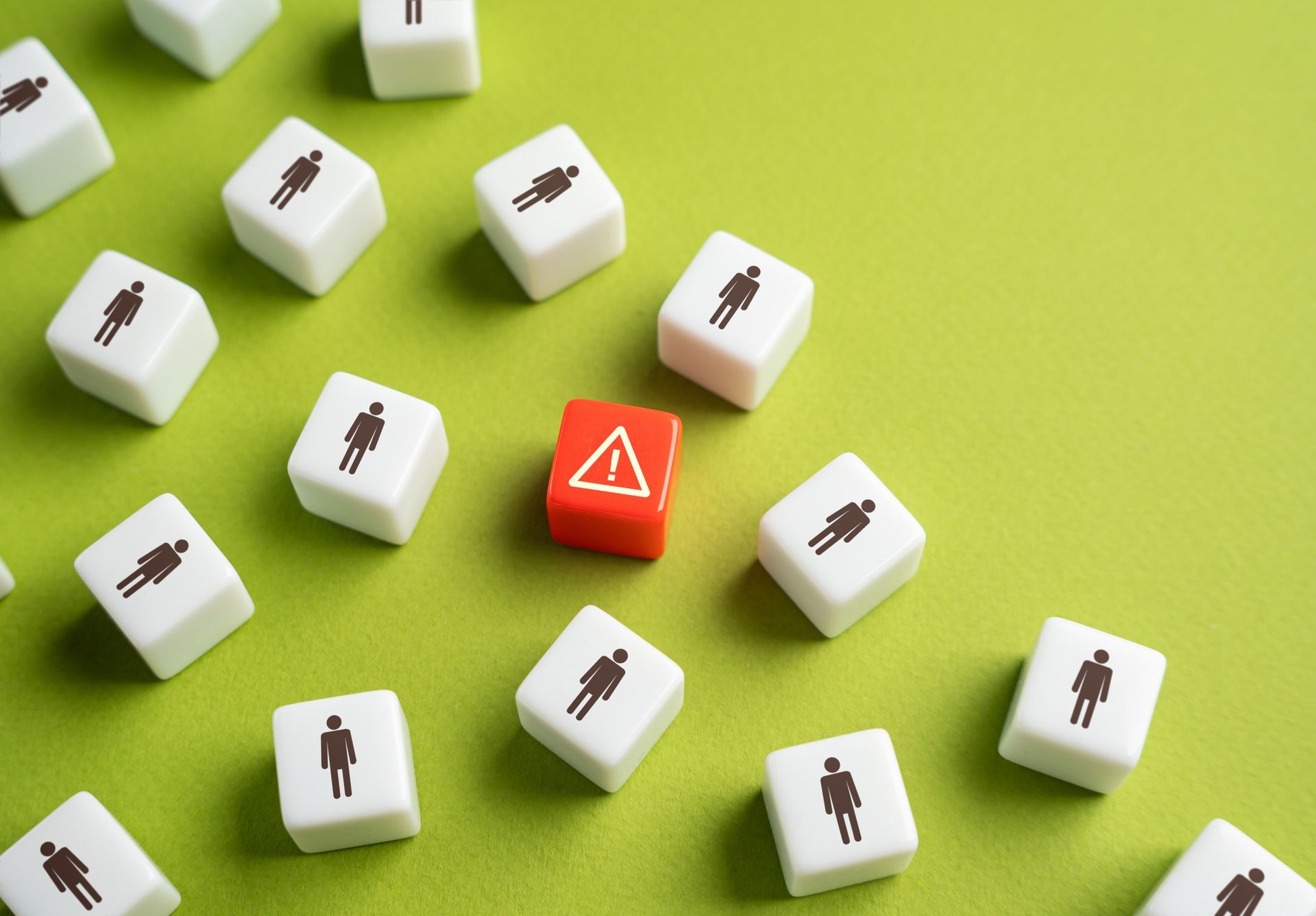 White blocks with stick figures scattered around a red block with an exclamation point on a green surface. White blocks with stick figures scattered around a red block with an exclamation point on a green surface.