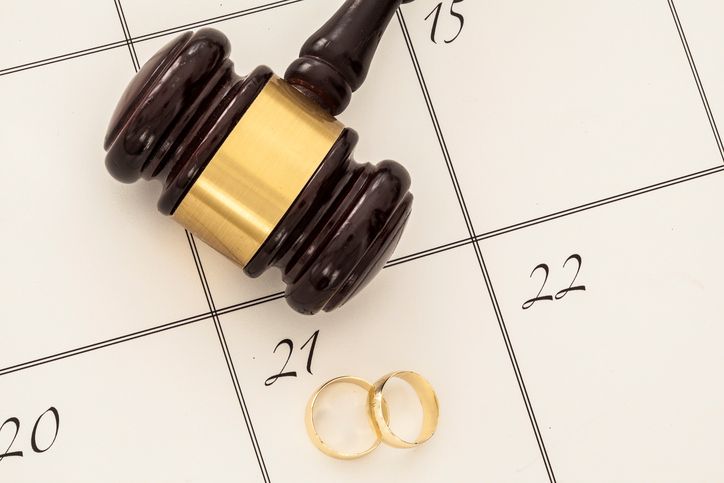 Wedding rings and gavel on a calendar, symbolizing divorce or legal separation.