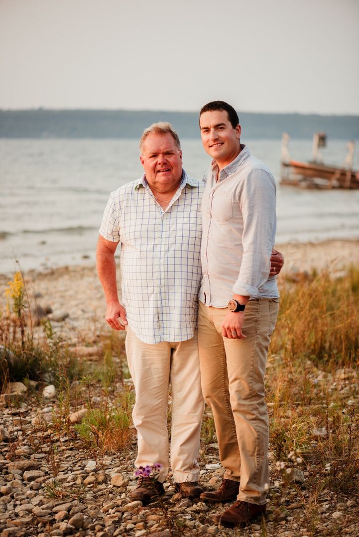 Father and son standing together near a lake.