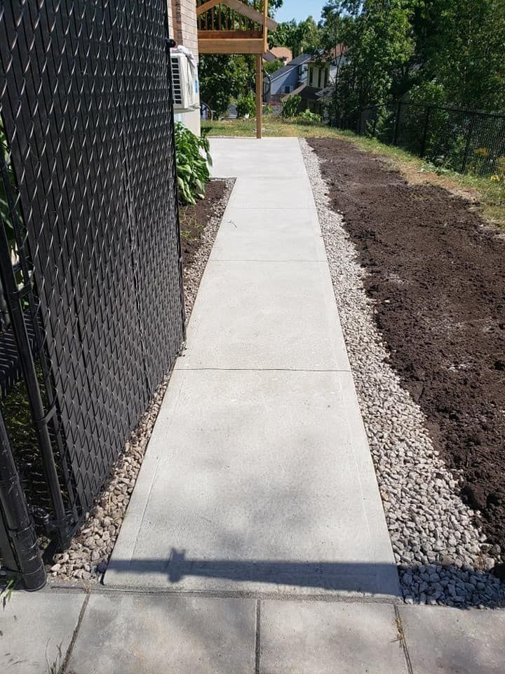 Une passerelle en béton est en cours de construction à côté d'une clôture.