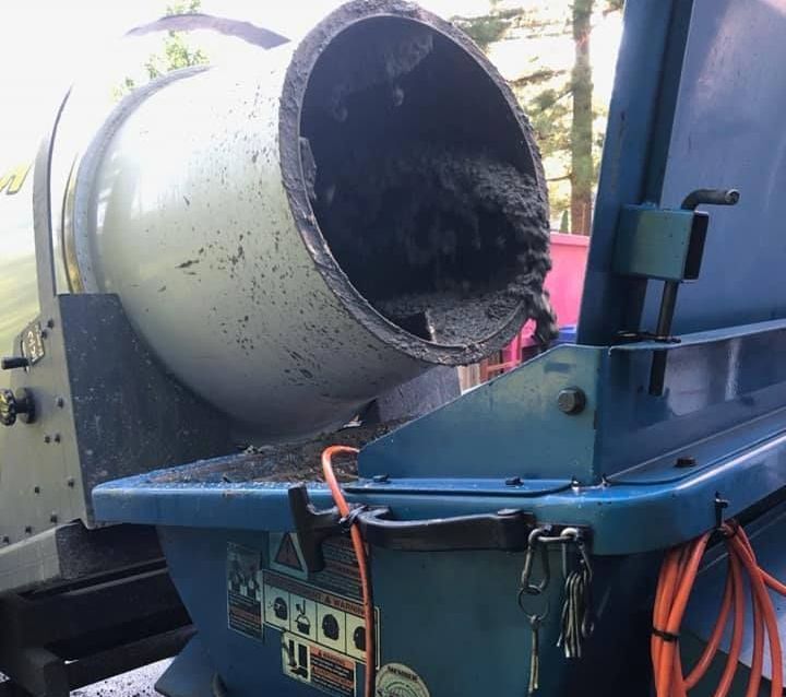 Une bétonnière verse du béton dans un récipient bleu