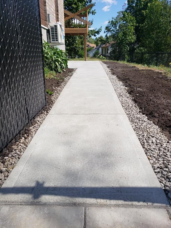 Une passerelle en béton menant à une maison par une journée ensoleillée.