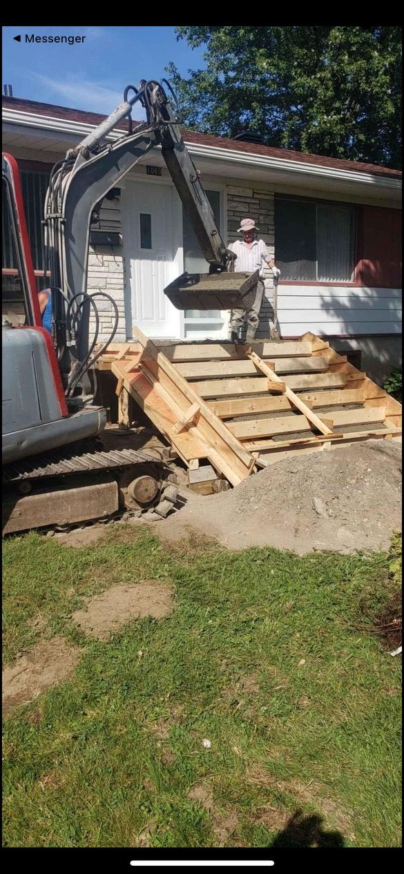 Un homme coule du béton sur une rampe en bois devant une maison.