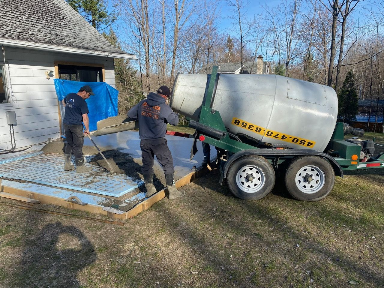 Une bétonnière est utilisée pour mélanger le béton devant une maison.