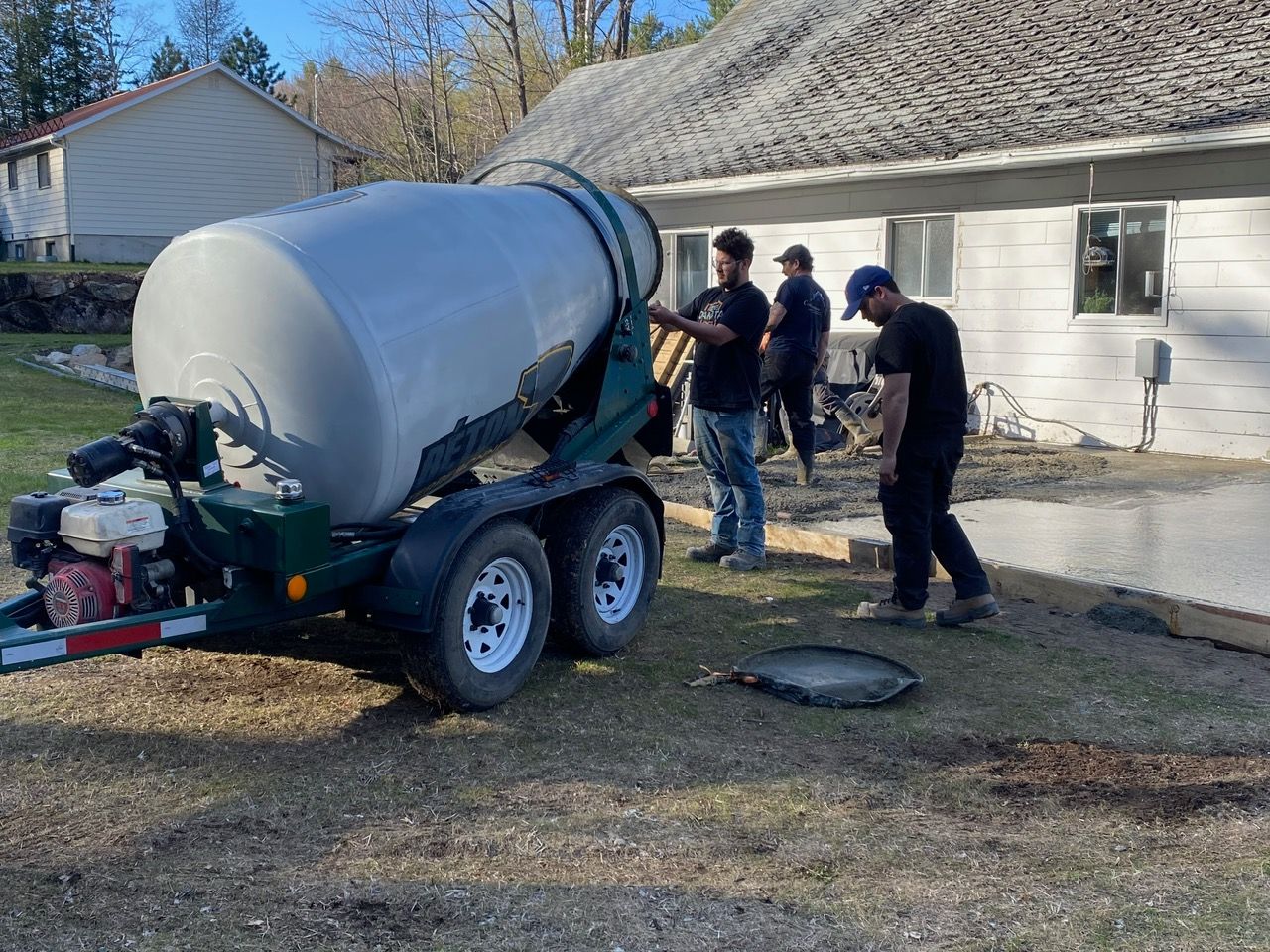 Bétonnière et ouvriers près d'une maison coulant du béton.