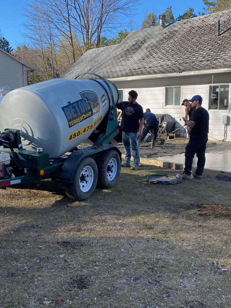 Une bétonnière est utilisée pour mélanger le béton devant une maison.
