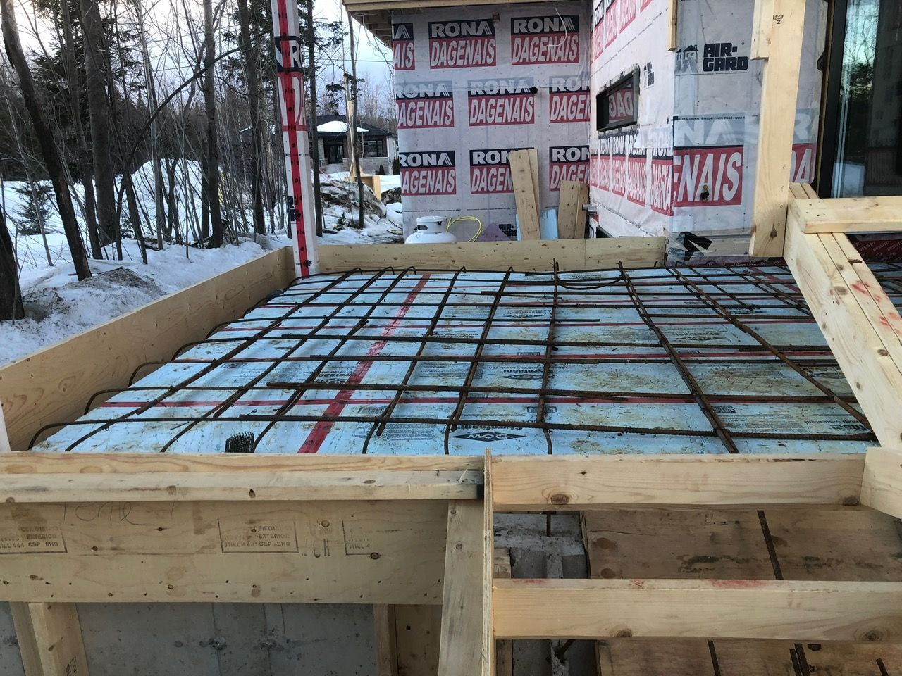 Cadre en bois supportant une grille d'armature sur de la mousse bleue, prêt à couler la dalle de béton. Cadre hivernal.