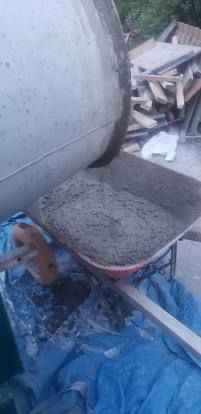 Une bétonnière verse du béton dans une brouette.