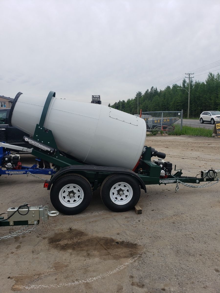 Une bétonnière est sur une remorque dans un parking