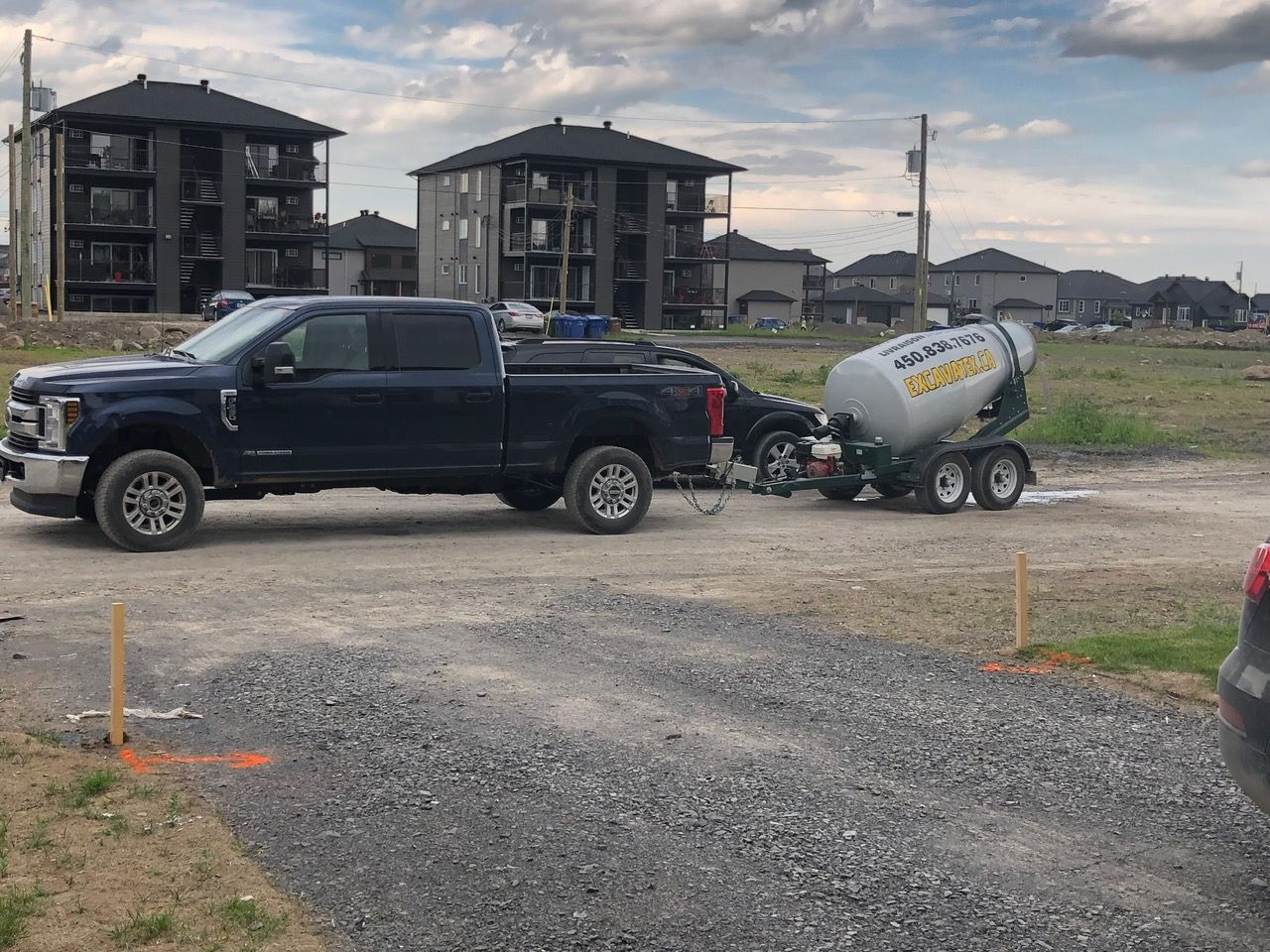 Un camion remorque une bétonnière sur une route de gravier.