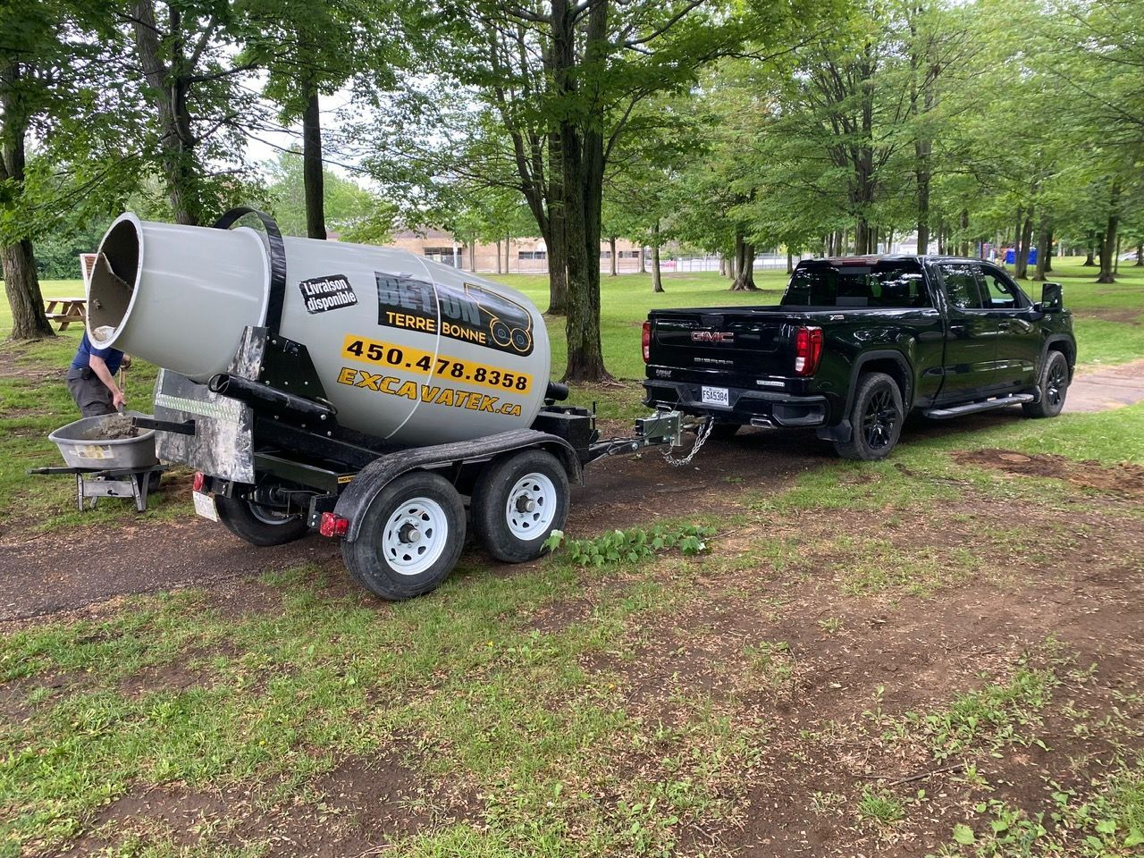 Un camion tire une remorque à laquelle est attachée une bétonnière.