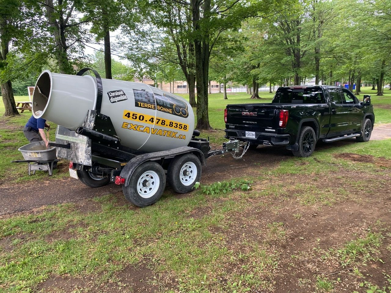 Un camion remorque une bétonnière sur une remorque.
