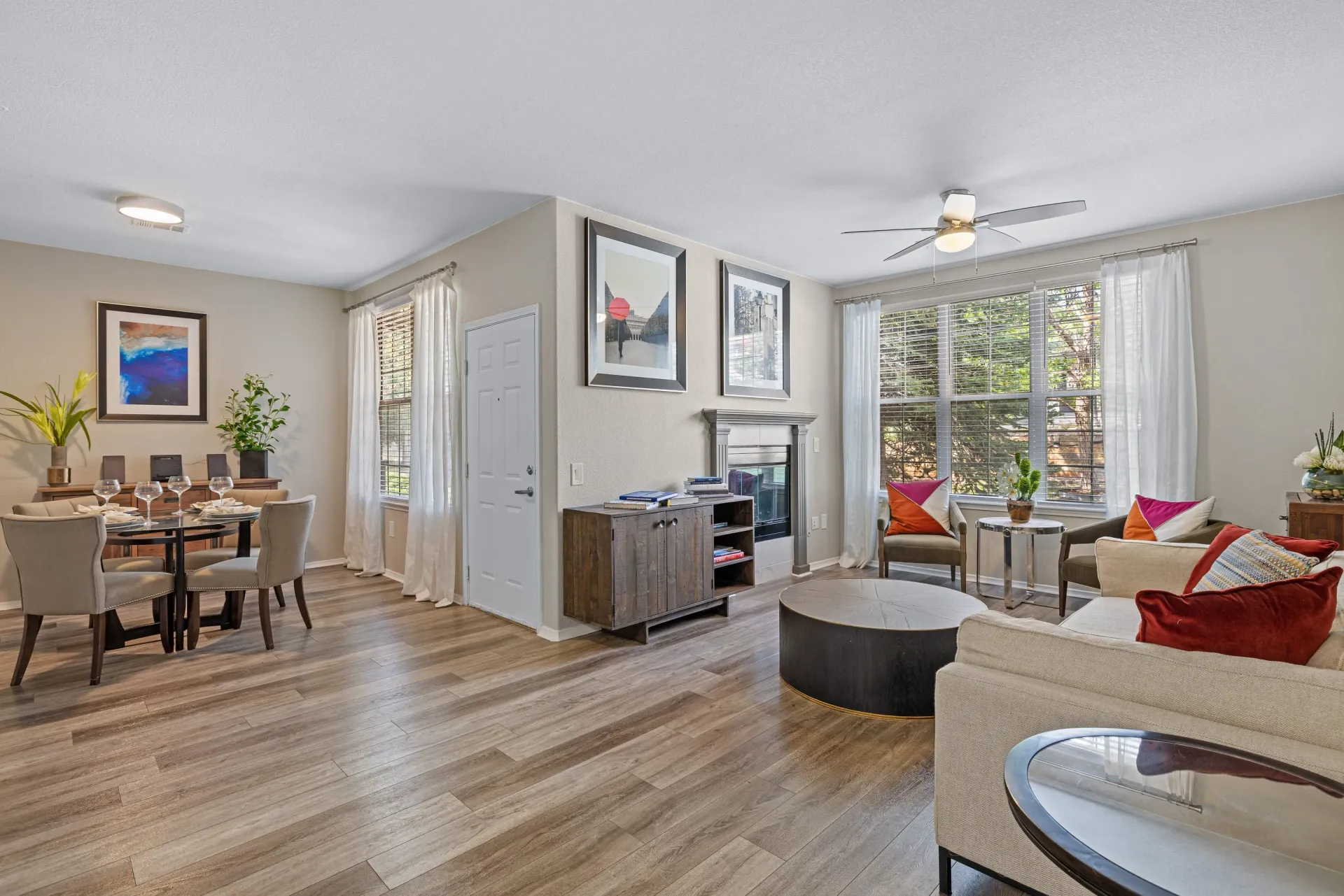 Bright open-plan living and dining area with large windows, fireplace, and neutral decor.