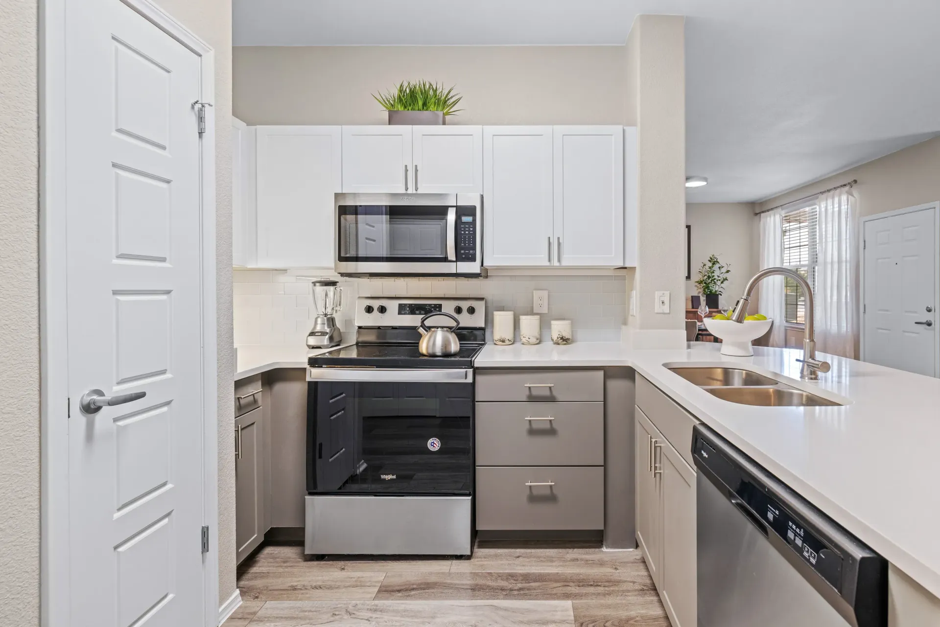 White kitchen with white cabinets, stainless steel appliances, and a double sink.