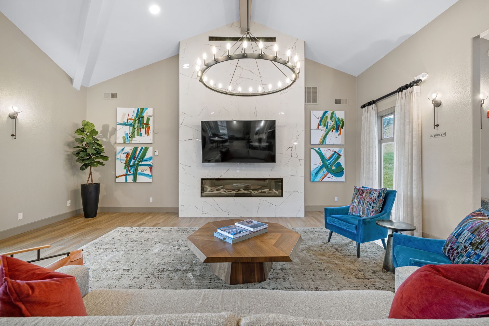 Living room with fireplace, TV, and blue armchairs, with a large rug and neutral walls.
