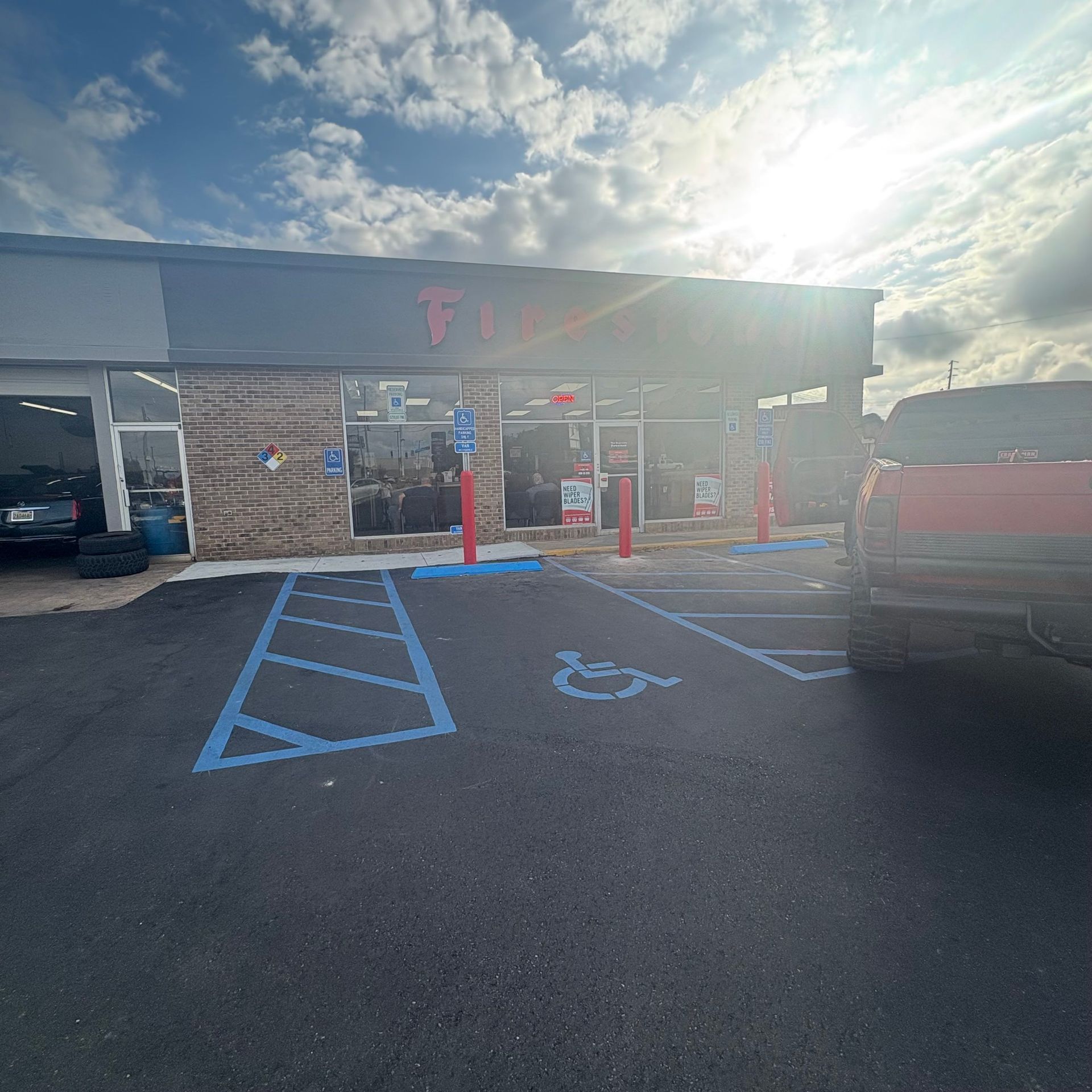 Sunny storefront with accessible parking spaces and a red SUV in front