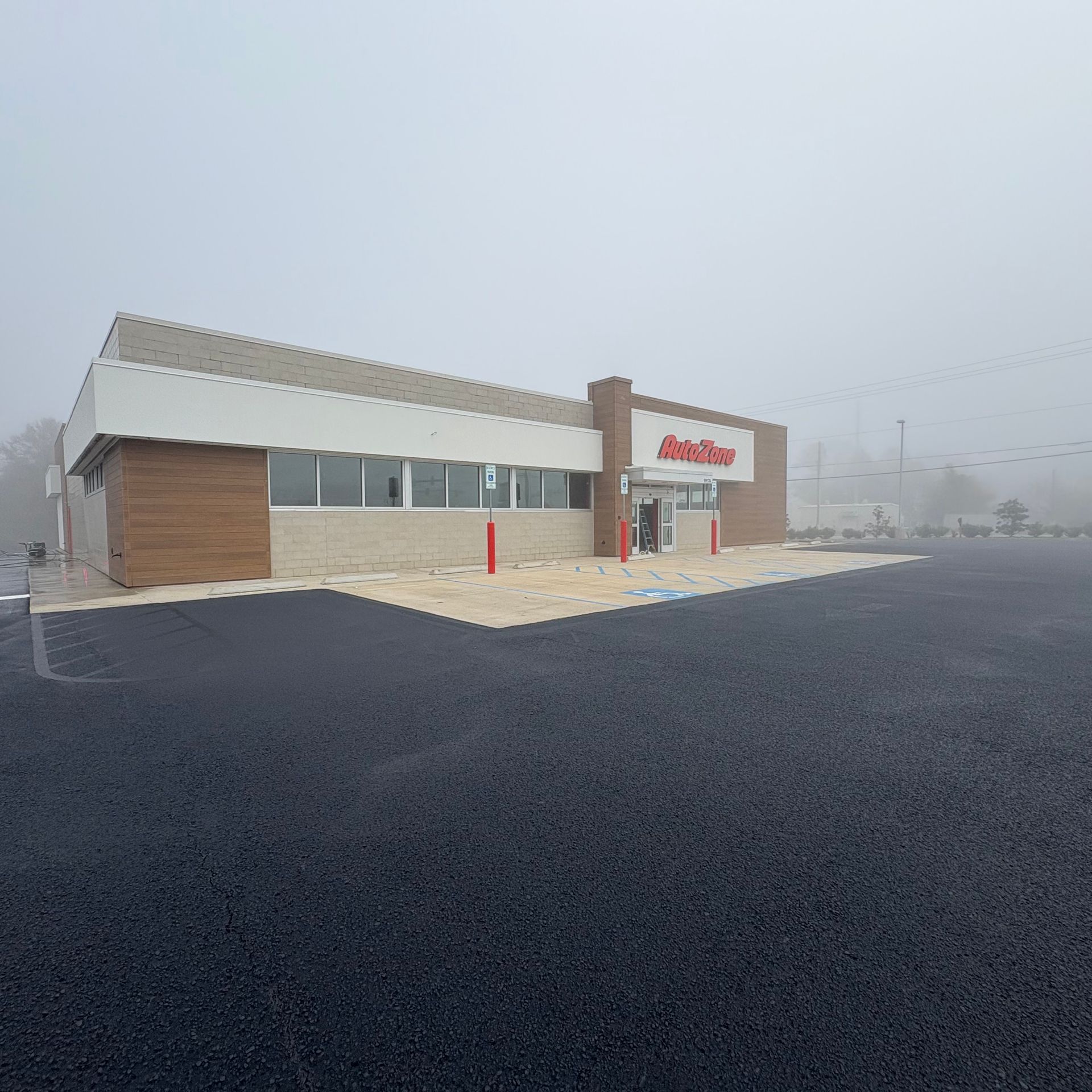 Foggy view of a commercial storefront with a red sign and empty parking lot