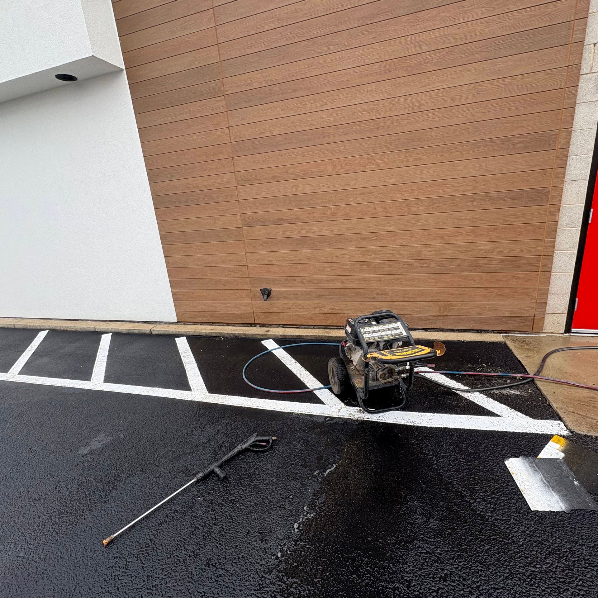 Damaged toy car on wet parking lot by a wooden wall, with debris nearby and a fallen rod in front