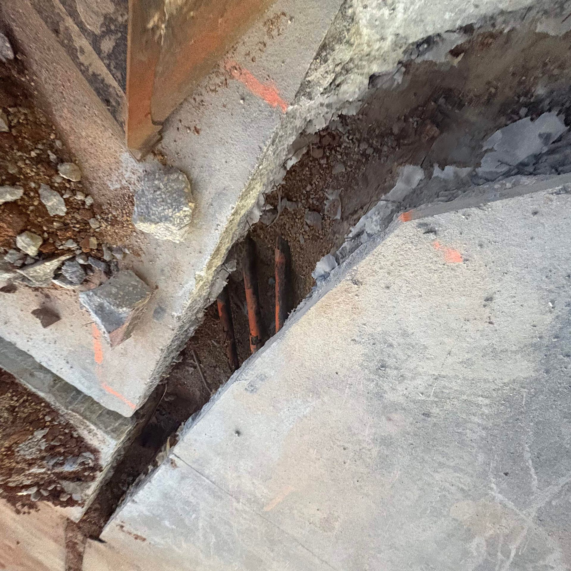Broken concrete slabs with a visible gap and rusted rebar in a damaged floor area