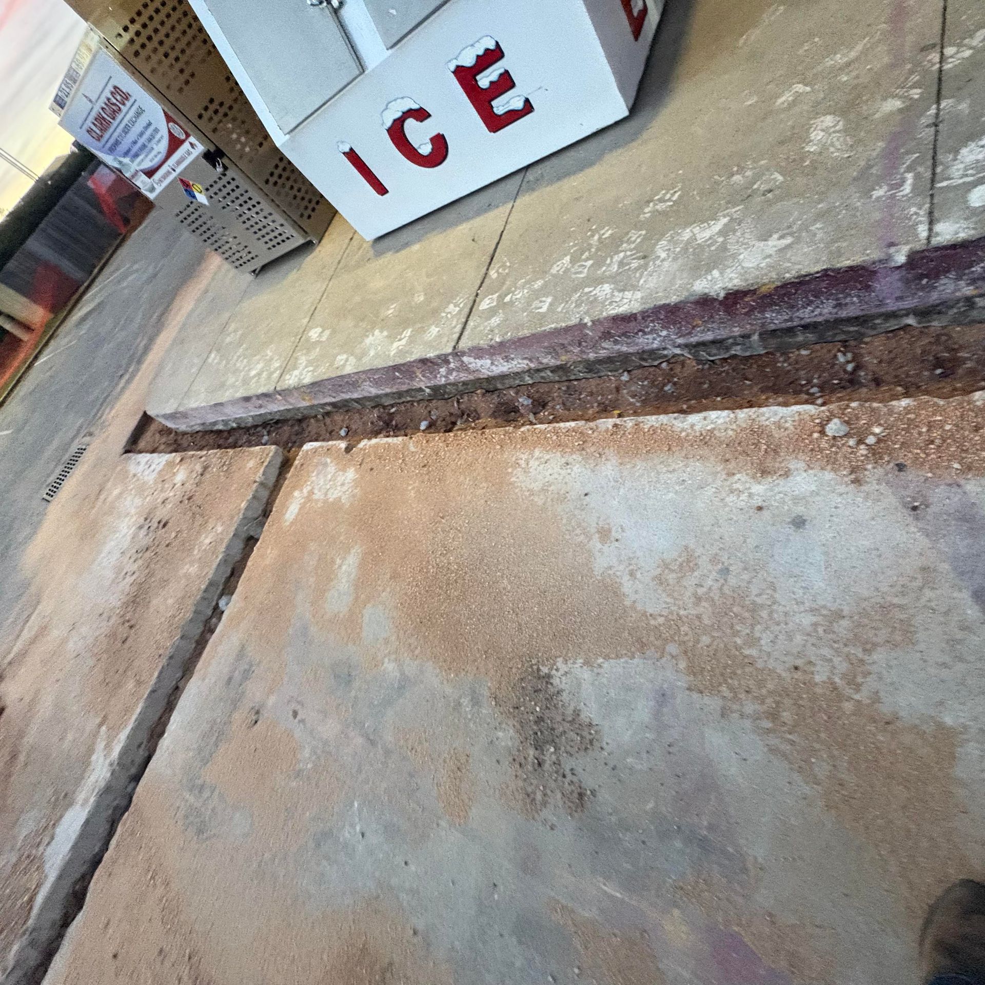 Concrete sidewalk with a metal strip and an ice cooler near a storefront entrance