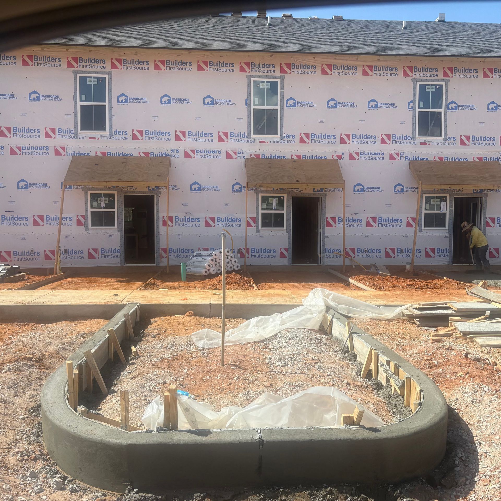 New row of houses under construction with wrapped siding and a concrete foundation in front