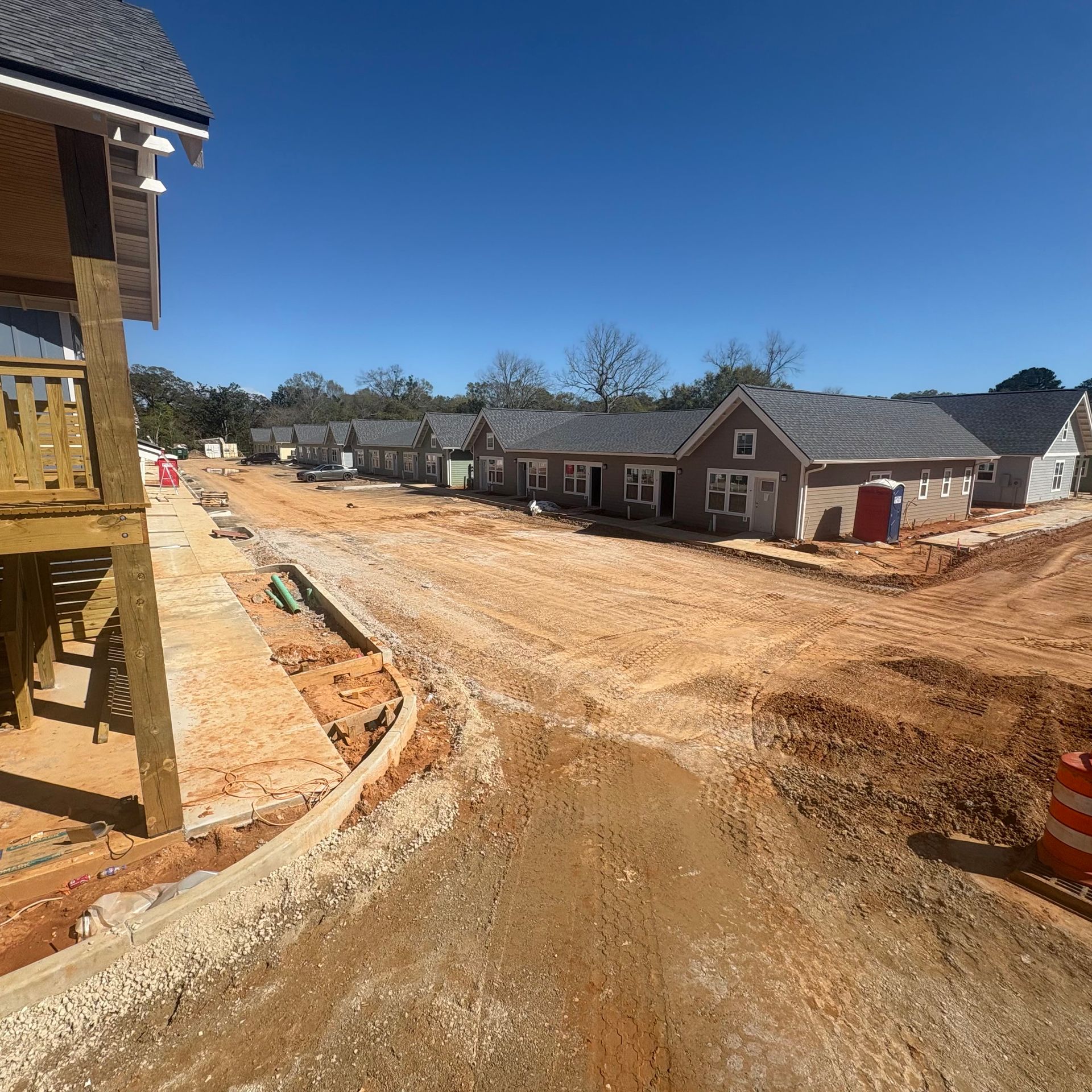 New home construction site with dirt road and partially built houses under a clear blue sky