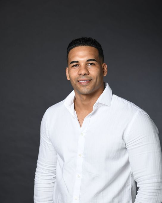 A woman is sitting at a desk with a laptop and a vase of flowers.