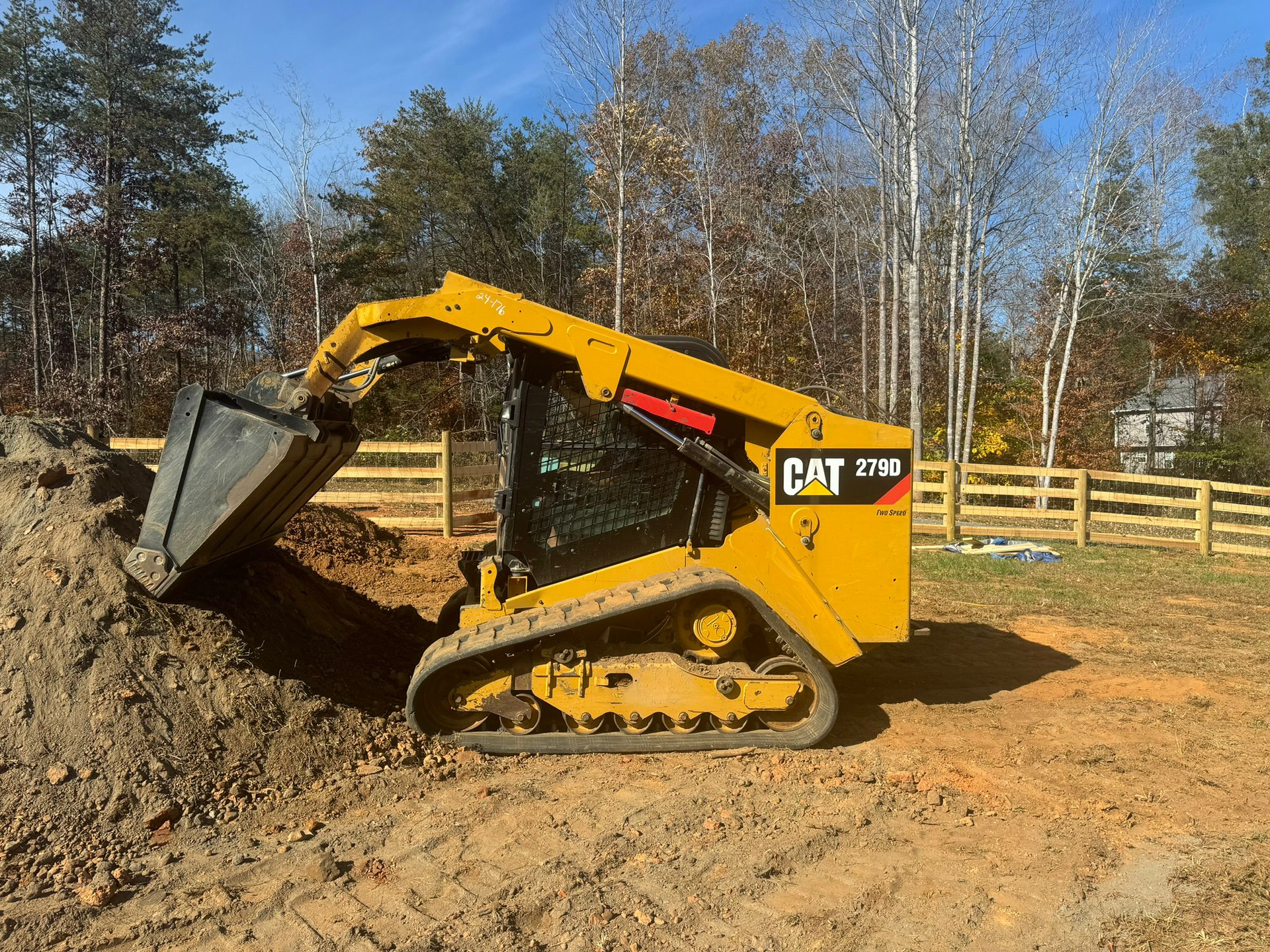 A yellow cat bulldozer is moving dirt in a field.