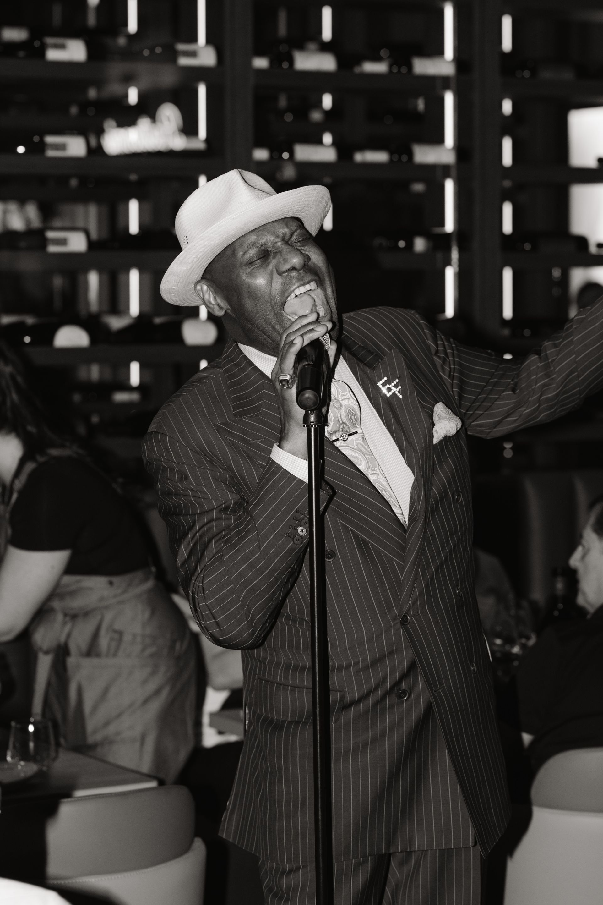A man in a suit and hat is singing into a microphone.