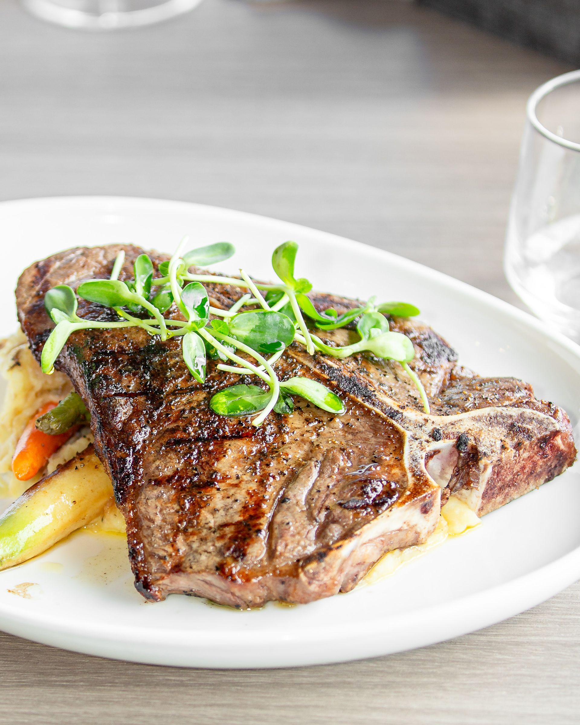 A white plate topped with a steak and vegetables on a table.